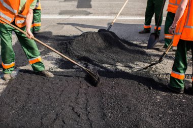 Road Street tamirat sırasında kaldırım makinesinde çalışan işçiler. Sokak yeniden ortaya çıkıyor. Taze asfalt yapısı. Kötü yol..