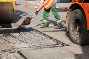 Road Street tamirat sırasında kaldırım makinesinde çalışan işçiler. Sokak yeniden ortaya çıkıyor. Taze asfalt yapısı. Kötü yol..