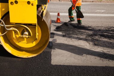 Otoyol inşaatı sırasında çakıl tabanının üstüne yeni asfalt ya da bitumen döşeyen asfalt makinesi..