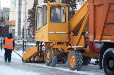 Traktör kardan yolu temizliyor. Kazıcı şehirdeki büyük miktardaki karları sokaklardan temizliyor. İşçiler kışın yolu kardan temizler, kar fırtınasından yolu temizler..