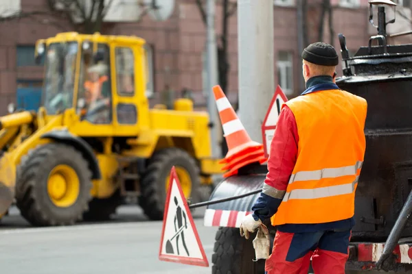 Turuncu üniformalı bir çalışan yol onarımını kontrol ediyor.. — Stok fotoğraf