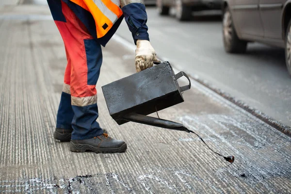 A worker pours liquid asphalt, molten bitumen from a bucket of resin. — Stock Photo, Image