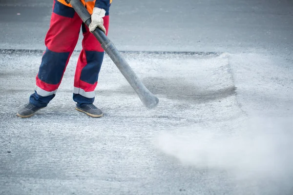 Operaio stradale taglio strada asfaltata, lavorando sulla ricostruzione stradale. taglio asfalto con spruzzatura ad acqua per trattenere la polvere . — Foto Stock