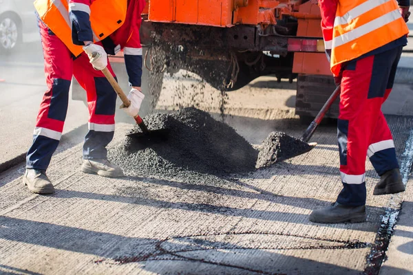 Giovane costruttore su asfaltatrice durante lavori di riparazione stradale. — Foto Stock