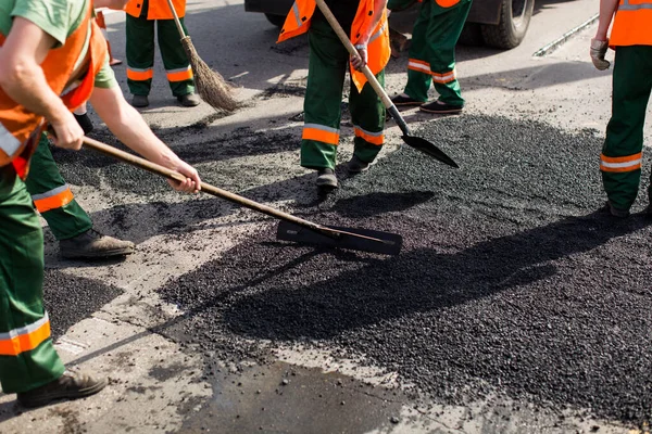 Workers on Asphalting paver machine during Road street repairing works. Street resurfacing. Fresh asphalt construction. Bad road.