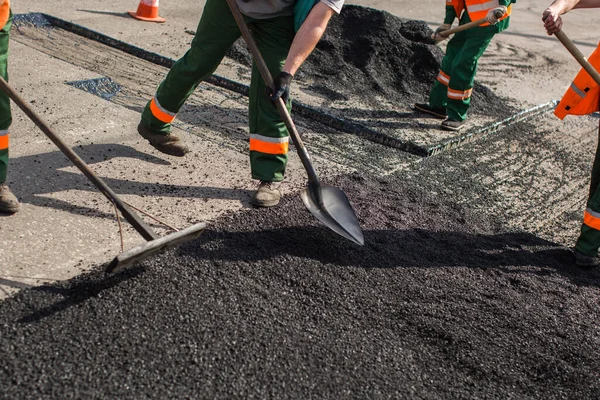 Bauarbeiter während Asphaltierungsarbeiten nivellieren Rohmaterial vor dem Betrieb der Maschine. — Stockfoto