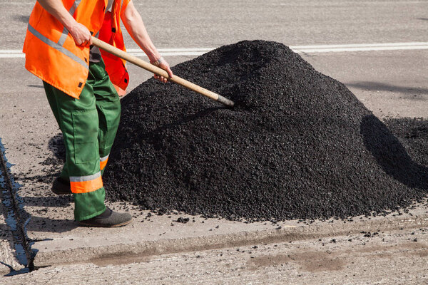 Repair of roads, highways and sidewalks. Patching. Working with a shovel falls asleep in the pit.