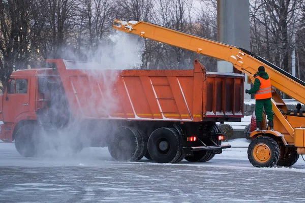 Trator limpando a estrada da neve. Escavadeira limpa as ruas de grandes quantidades de neve na cidade. Os trabalhadores varrem a neve da estrada no inverno, limpando a estrada da tempestade de neve. — Fotografia de Stock