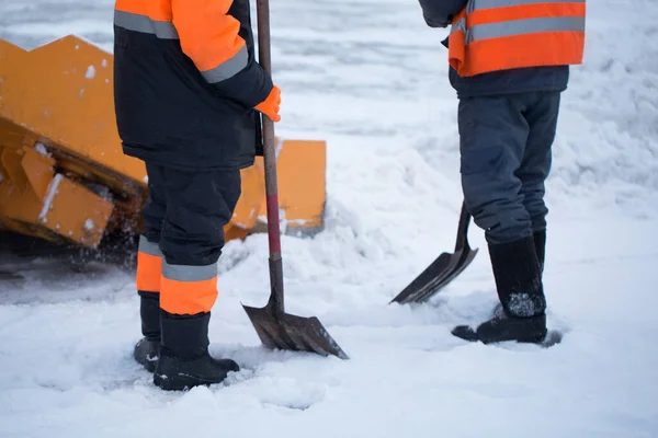 Traktör kardan yolu temizliyor. Kazıcı şehirdeki büyük miktardaki karları sokaklardan temizliyor. İşçiler kışın yolu kardan temizler, kar fırtınasından yolu temizler.. — Stok fotoğraf