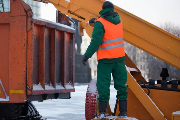 Tractor limpiando la carretera de la nieve. Excavadora limpia las calles de grandes cantidades de nieve en la ciudad. Los trabajadores barren la nieve del camino en invierno, limpiando el camino de la tormenta de nieve. — Foto de Stock