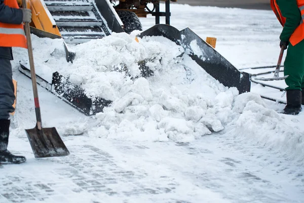 Tractor limpiando la carretera de la nieve. Excavadora limpia las calles de grandes cantidades de nieve en la ciudad. Los trabajadores barren la nieve del camino en invierno, limpiando el camino de la tormenta de nieve. — Foto de Stock