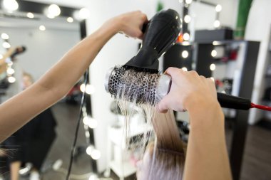 Saç kurutma makinesi ve yuvarlak fırçalı uzun sarı saçlar..