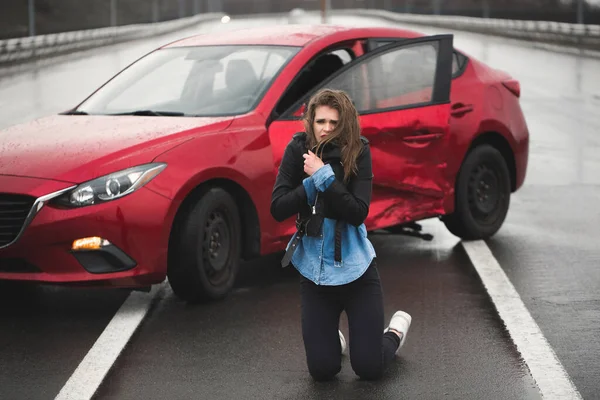 Mujer sentada en la carretera después de un accidente. Mujer lesionada sintiéndose mal después de tener un accidente de coche . — Foto de Stock