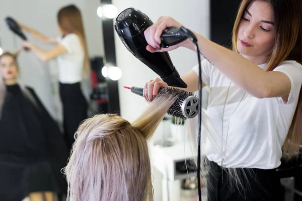 Secagem de cabelo loiro longo com secador de cabelo e escova redonda . — Fotografia de Stock