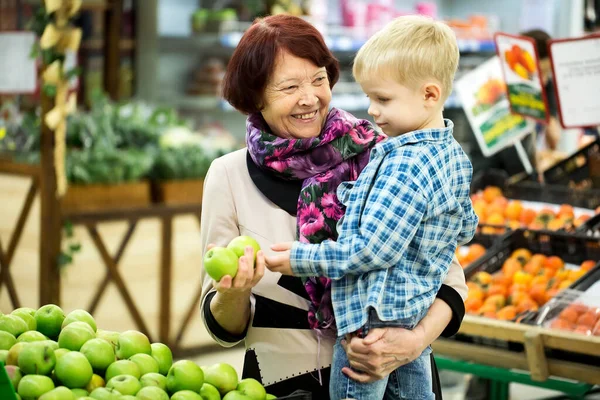 Бабушка и внук выбирают фрукты Apple во время покупок в овощном супермаркете . — стоковое фото