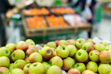 Süpermarkette kutuların üzerinde yeşil ve kırmızı elmalar.