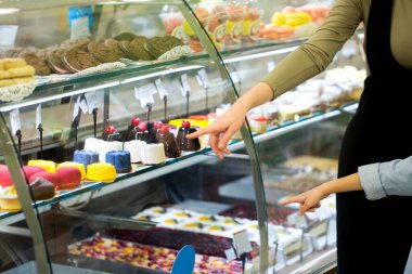 Çocuklu genç bir aile, büyük bir süpermarketin vitrininde tatlıyı seçiyor..