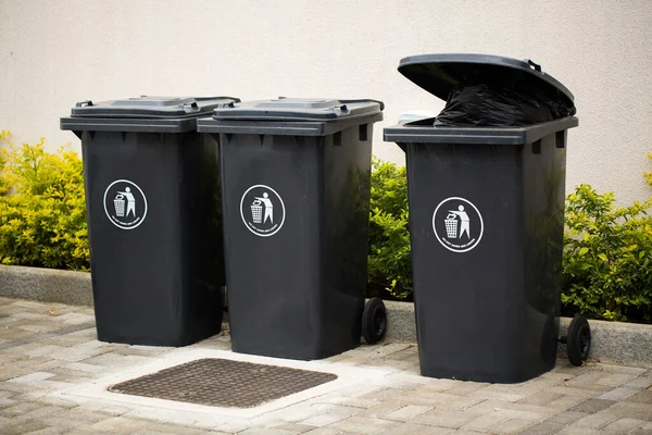 Black indoor waste containers for recycling and garbage. A lot of closed and recycle receptacles trash bin outside.