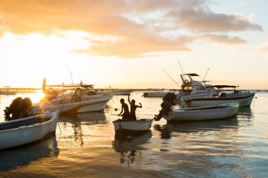 Gün batımında bir teknede çocukların silueti. balık.