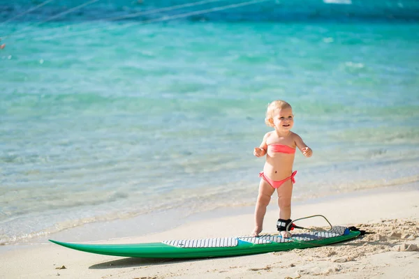 Ein kleines Mädchen lernt auf dem Hintergrund des blauen Ozeans surfen. — Stockfoto