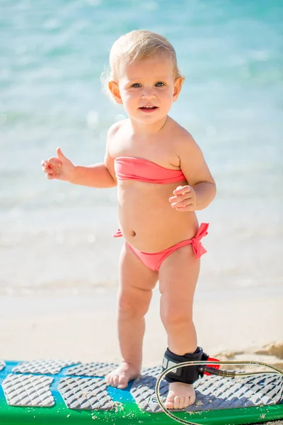 Ein kleines Mädchen lernt auf dem Hintergrund des blauen Ozeans surfen. — Stockfoto