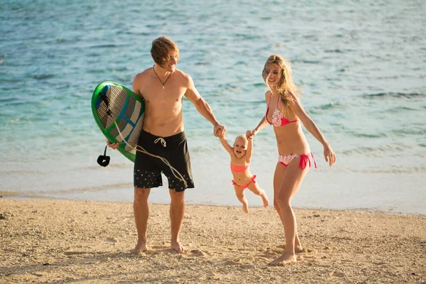 Mladé a krásné rodiče hrát se svou dcerou na pláži. — Stock fotografie