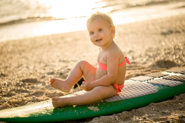 Ein kleines Mädchen lernt auf dem Hintergrund des blauen Ozeans surfen. — Stockfoto