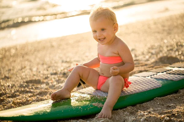 Ein kleines Mädchen lernt auf dem Hintergrund des blauen Ozeans surfen. — Stockfoto