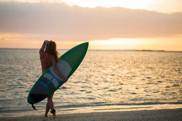 Surfařská surfařka hledící na západ slunce na pláži oceánu. Silueta ženských bikin žena při pohledu na vodu se stojící s surfovací prkno baví žít zdravý aktivní životní styl. Vodní sporty s modelem. — Stock fotografie