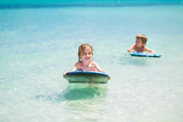 Zwillinge Bruder und Schwester haben Spaß beim Surfen im Meer. — Stockfoto