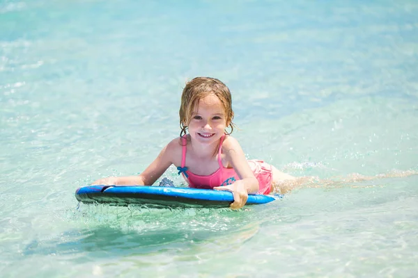 Liten flicka - ung surfare med bodyboard har roligt på små havsvågor. Aktiv familjelivsstil. — Stockfoto