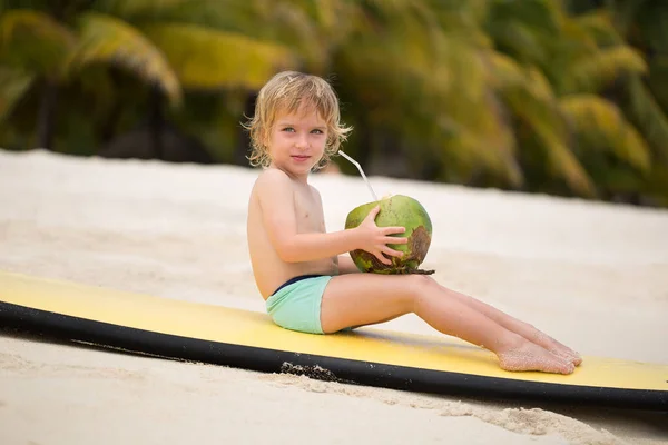 Χαρούμενο αστείο μικρό παιδί προσχολικής ηλικίας που πίνει χυμό καρύδας στην παραλία του ωκεανού.. — Φωτογραφία Αρχείου