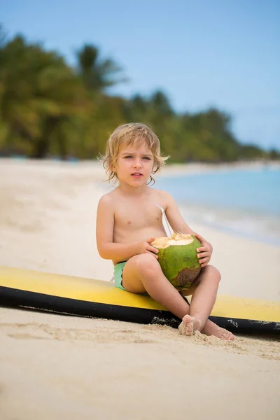 Glücklich lustige kleine Vorschulkind Junge trinkt Kokossaft am Strand. — Stockfoto