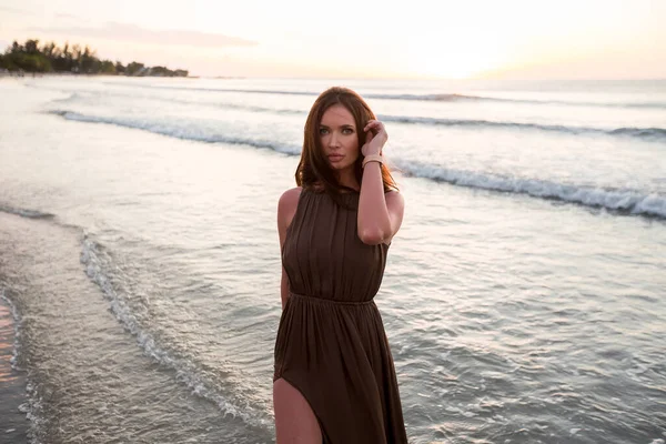 Mooie vrouw op zonsondergang achtergrond. Kleurrijke dageraad boven de zee. Zorgeloze vrouw die geniet van de zonsondergang op het strand. Gelukkige levensstijl. — Stockfoto