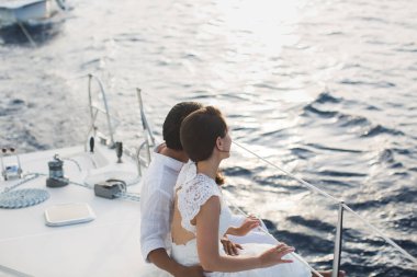 Düğün çifti bir yatta kucaklaşıyor. Damat ile güzel gelin.