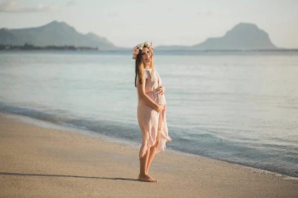 Mujer embarazada en un hermoso vestido en el océano . —  Fotos de Stock