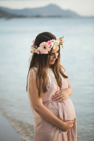 Zwangere vrouw in een prachtige jurk op de oceaan. — Stockfoto