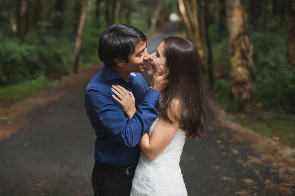 Gelin ve damat, yeşil arka planda ormanda öpüşen yeni evliler.. — Stok fotoğraf