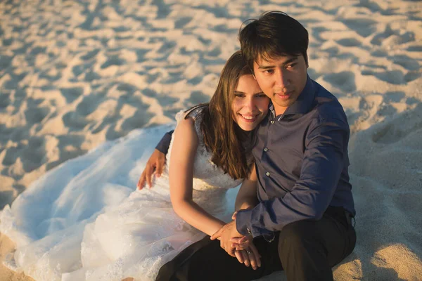 Νύφη και γαμπρός κάθονται στην άμμο. — Φωτογραφία Αρχείου