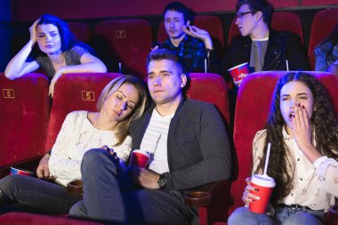 Gençler sinemada sıkıcı bir film izliyor, kızlar uyuyor..