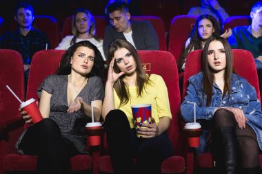 Sinema salonunda çok sıkıcı bir film izleyen kızlar. Kötü film..