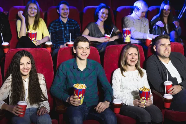 Друзья сидят в кинотеатре и смотрят фильм, едят попкорн и пьют газированную сладкую воду. Кино и развлекательная концепция . — стоковое фото