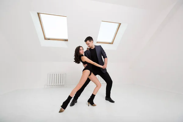 Schönes Paar tanzt Bachata auf weißem Hintergrund im Studio. — Stockfoto