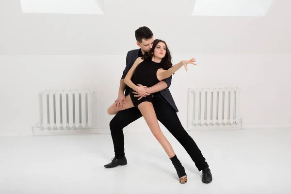 Lindo casal dança bachata no fundo branco no estúdio . — Fotografia de Stock