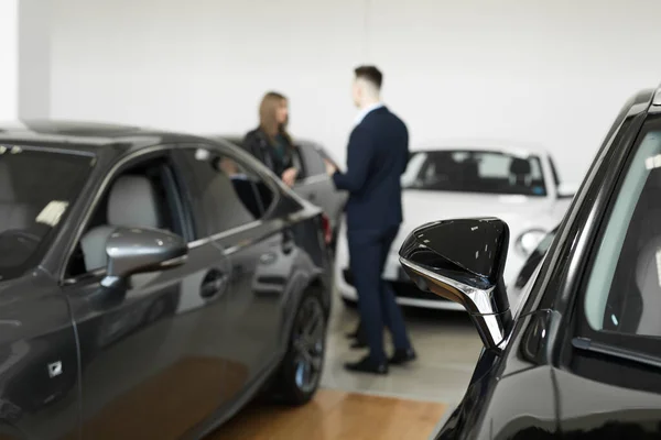 Auto business, car sales - a couple of friends of girls with a car dealer choose a car in a car dealership — Stock Photo, Image