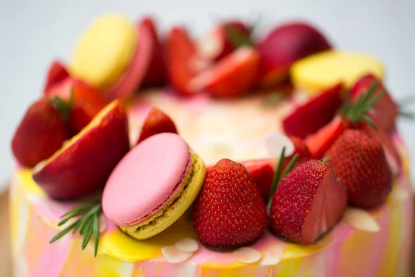Cake yellow and pink splotches, strawberries, peaches, macaroons, rosemary.