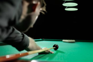 Bilardo topuna bilardo sopasıyla nişan alan bir adam..