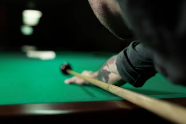 Bilardo topuna bilardo sopasıyla nişan alan bir adam..