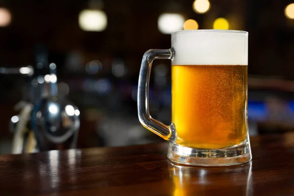 Glass of light beer on a dark pub. — Stock Photo, Image