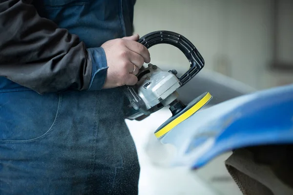 Um homem que lixar com um moedor e prepara a tinta para o carro em um serviço de carro. Reparador consertar pintura de carro — Fotografia de Stock